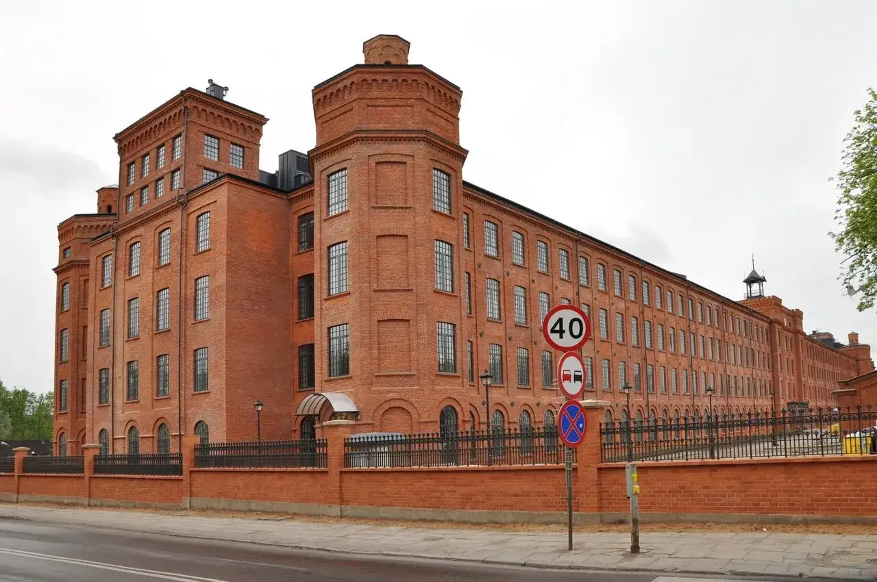 Imponujący Księży Młyn, idealne miejsce na zwiedzanie. Ceglana architektura zachwyca, a znaki drogowe sugerują spokojne tempo.