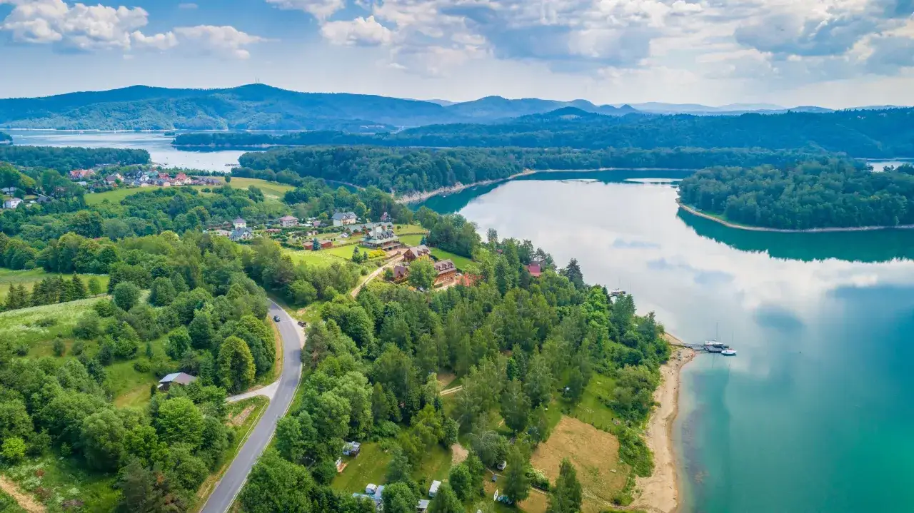 Widok z lotu ptaka na malowniczą zatokę, która przypomina serce w Bieszczadach. Otoczona lasami i górami, z domkami i łodziami przy brzegu.