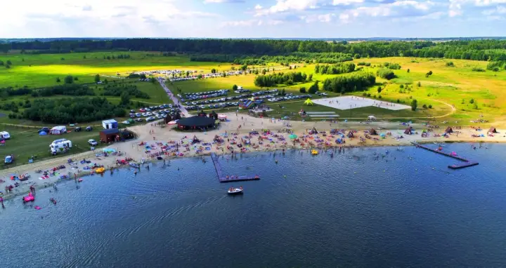 Tłumy ludzi wypoczywają na plaży i w wodzie. Idealne miejsce, gdzie nad wodę Dolny Śląsk zaprasza na wakacje.